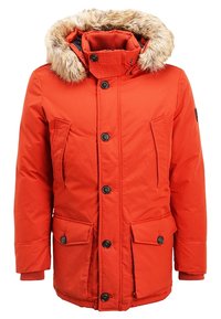 Červená parka s kapucí lemovanou umělým kožíškem, zapínáním na zip a knoflíky, čtyřmi předními kapsami a žebrovanými manžetami. Hladký povrch a zateplený design.