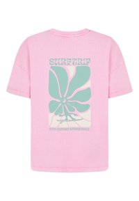 Roze katoenen t-shirt met een losse pasvorm, met een grafisch ontwerp in groen en crème waar in bold lettertype "SURFTRIP" op staat.