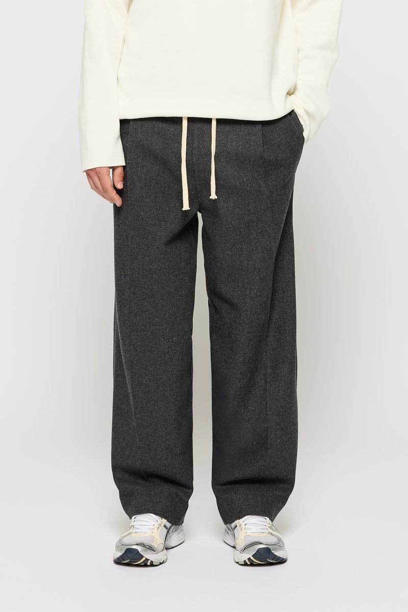 Grå, vide bukser lavet af tekstureret stof, med en drawstring talje og cremefarvede snore. Kombineret med hvide og grå sneakers.