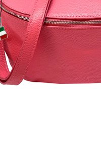 Roze leren schoudertas met een textuurafwerking, voorzien van een zilveren ritssluiting en een klein Italië vlag charm aan de strap.