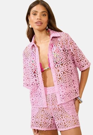 Roze kant twee-delig set bestaande uit een shirt met korte mouwen en knopen aan de voorkant, met bijpassende shorts, die grafische bloemenpatronen en uitsnijdingen toont.