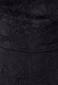 Black crinkled fabric with a textured appearance, featuring deep folds and creases, creating a layered and uneven surface.