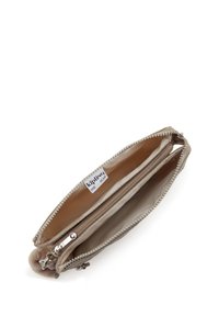 Beige Kipling Geldbörse mit Reißverschluss-Fächern und einem flauschigen Schlüsselanhänger, geöffnet, um die Innenfächer zu zeigen.