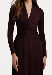 Långärmad klänning i djup bordeaux, med en tvistdetalj vid halsen och en figurnära silhuett. Slät, elastisk tyg och strömlinjeformat design.