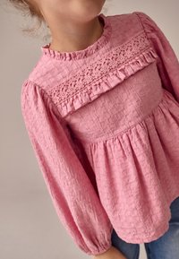 Roze blouse met textuur en lange pofmouwen, met een horizontale kanten inzet met bloemmotieven en een taille die is geplooid.