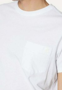 Hvid bomulds t-shirt med rund halsudskæring og korte ærmer, en venstre brystlomme og diskret logo. Letvægtig tekstur.