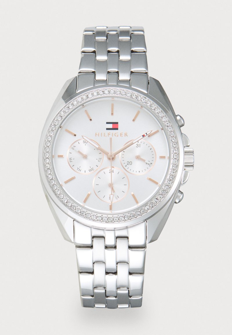 Orologio in metallo argento con grande quadrante rotondo, quadrante bianco, dettagli in oro rosa, tre sottodial e una lunetta incrustata di cristalli. Le maglie sono lucidate.