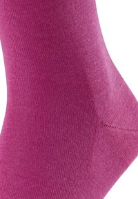 Fuksjowe skarpetki o gładkiej teksturze, z prążkowanym wzorem i wzmocnionym piętą. Materiał wydaje się elastyczny i oddychający.