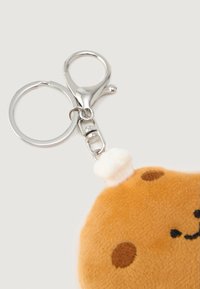 Silver key ring with clasp attached to a plush bear face keychain wearing a small white chef hat.