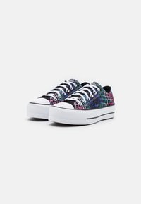 Zapatillas coloridas con un patrón multicolor texturizado sobre un fondo negro. Presentan cordones blancos y una suela blanca gruesa con acentos negros.