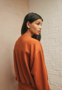Ruskvärgad oversized sweatshirt med ribbade avslut, rund halsringning och sänkt axel. Mjuk textur med minimala sömdetaljer.