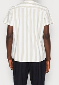 Korte mouwen shirt met een beige en wit verticaal gestreept patroon, met een standaard kraag en een yoke detail op de rug.