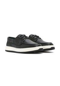 Scarpe in pelle nera con una texture liscia, dotate di una suola intermedia bianca e un sistema di allacciatura distintivo. Punta arrotondata e design a profilo basso.