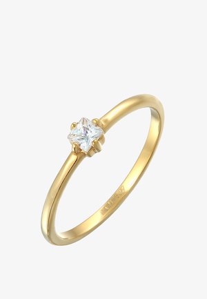 Guldringe med en glat ringform, der har en prongsat, klar princess-cut ædelsten i midten. Enkel, elegant design uden yderligere udsmykninger.