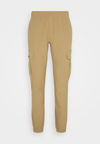 Pantalons cargo beige avec une taille élastique, des jambes fuselées et deux poches cargo latérales avec rabats et fermetures à bouton. Texture de tissu lisse.