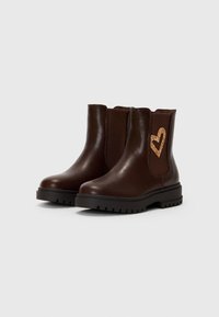 Botas de cuero marrón hasta el tobillo con paneles laterales elásticos texturizados y un detalle de corazón brillante. Suela de goma negra resistente con un patrón estriado.