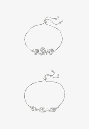 Kaksi hopeista rannekorua: toinen kukkakuvioinen, jossa kiviä, toinen aaltomallinen ja kiillotettu. Molemmissa säädettävät ketjut helmillä.