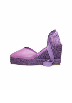 Zapato espadrille de cuña morado con puntera cerrada, tacón tejido y lazo para atar en el tobillo sobre fondo blanco.