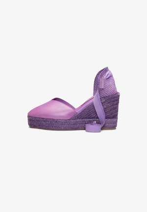 Zapato espadrille de cuña morado con puntera cerrada, tacón tejido y lazo para atar en el tobillo sobre fondo blanco.