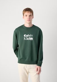 Tmavozelený crewneck svetrový pulóver s bielym logom "Calvin Klein", rebrovanými manžetami a lemovaním; vyrobený z mäkkej tkaniny s hladkou štruktúrou.