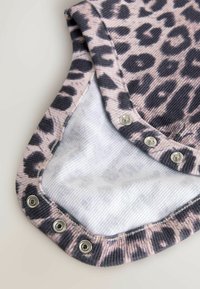 Patted leopard-print stof med lyserøde og grå nuancer, med trykknaplukninger langs kanten og et blødt hvidt inderskud.