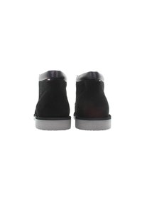 Botines de ante negros con un cuello de cuero, suelas de goma grises y un detalle de costura mínimo. Diseño limpio y redondeado sin acentos visibles.