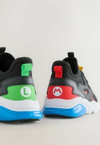 Black athletic shoes featuring green and red accents on the heels, with logos, a white midsole, and a blue rubber outsole.