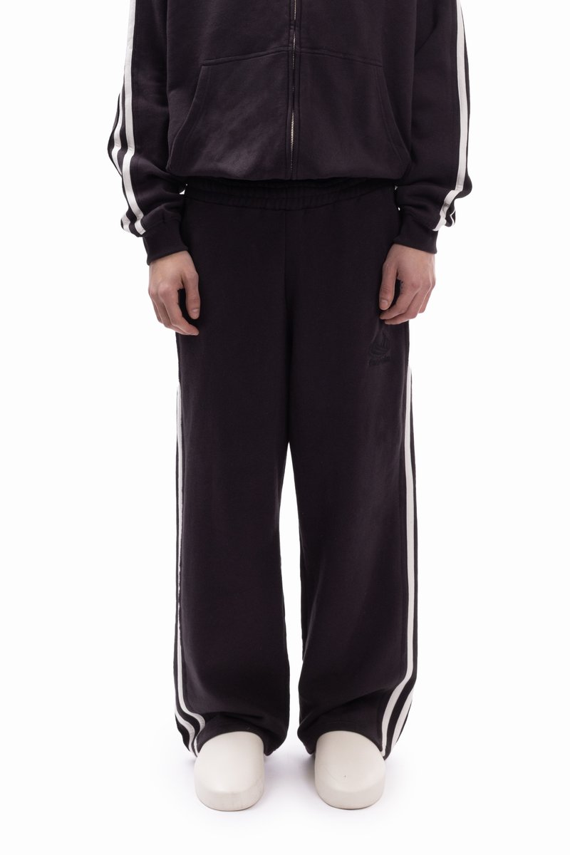 Μαύρο παντελόνι φόρμας με λευκές ρίγες στο πλάι, ελαστική μέση, άνε τη εφαρμογή και λεπτομέρεια με λογότυπο στο αριστερό μηρό. Μαλακό, υφασμάτινο με υφή.