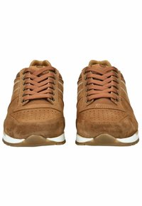 Sneaker in suede marrone con tomaia perforata, lacci beige, suola bianca e sottili strisce bianche di lato, dotate di punta arrotondata e linguetta imbottita.