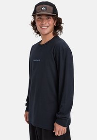 Navy long-sleeve t-shirt with a round neckline and Quiksilver logo, paired with a black and brown cap featuring a logo patch.