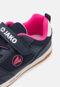 Marineblauwe sportschoen met roze accenten. Beschikt over een klittenbandsluiting, een bovenwerk van mesh, een rubberen zool en een logo in het midden.