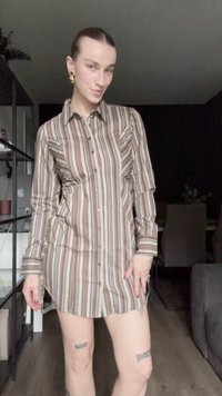 Camisa de botão às riscas em bege, castanho e branco, com colarinho, mangas longas e bolsos frontais, com uma bainha curva a meio da coxa.