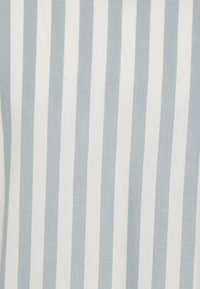 Tessuto di cotone con strisce verticali alternate di azzurro chiaro e bianco. La trama appare liscia e leggermente tessuta, migliorando la profondità visiva.