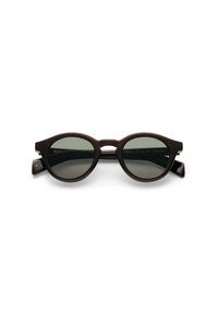 Mustat ovaalit aurinkolasit tummanharmailla linsseillä, joissa on paksu kehysdesign ja ainutlaatuiset sivuakkenteet. Koristeltu kaiverretulla brändäyksellä.