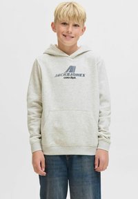 Hellegrauer Hoodie mit einer Vordertasche, ausgestattet mit einem blauen Grafiklogo und Akzenten. Lange Ärmel und eine Kordelzugkapuze. Jeans sind darunter sichtbar.