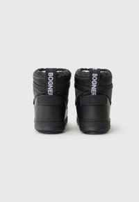 Botas de inverno pretas com um design acolchoado e um logótipo distinto na parte de trás. As solas são texturizadas, adequadas para vários tipos de terreno.