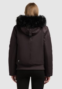 Schwarze kurze Jacke mit einer Kapuze aus Kunstpelz, glatter Textur, gerippten Bündchen und einem Logo-Tag an der unteren Seite. Entworfen für Wärme und Schutz.