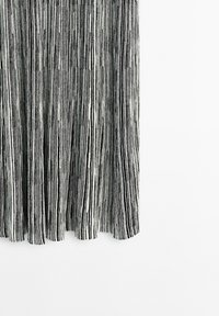 Robe en tricot présentant des rayures verticales noires et blanches, avec un motif texturé qui ajoute de la profondeur et de la dimension au tissu.