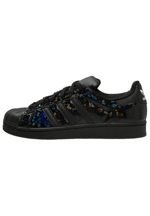 Baskets basses Adidas noires avec un motif tacheté multicolore brillant, des lacets noirs, trois bandes noires et un design à embout coquille.