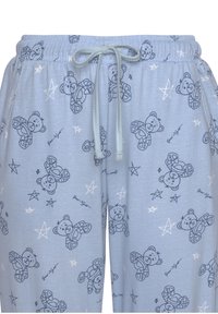 Svetlomodré pyžamové nohavice vyrobené z jemného materiálu, s opakujúcim sa vzorom medvedíkov a hviezd, s elastickým pásom a šnúrkou.
