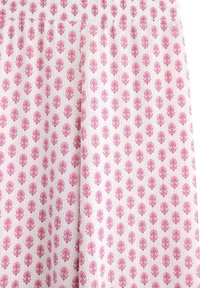 Lätt tyg med ett upprepande blommönster i rosa på vit bakgrund. Elastisk midja med rynkad textur.