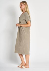 Hellbraunes Midikleid mit kurzen Ärmeln, V-Ausschnitt und Seitenschlitzen. Hergestellt aus weichem Stoff, mit legerer Passform und minimalistischem Design.