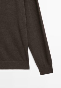 Maglione lavorato a maglia marrone scuro a maniche lunghe, con manica e lato mostrati su uno sfondo bianco, evidenziando il polsino e l'orlo a coste.