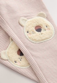 Ružovo-biela pruhovaná látka s aplikáciami plyšových medvedích tvárí s vyšívanými detailmi, mäkkou textúrou a okrúhlymi tvarmi.