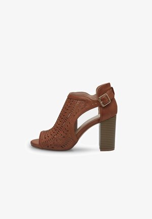 Sandalias de tacón perforadas en color marrón con punta abierta, diseño recortado y correa con hebilla en el tobillo. Tacón bloque robusto y texturizado.