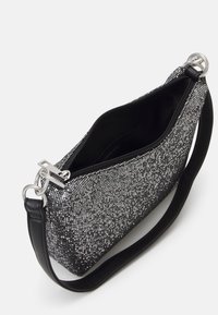 Borsa a tracolla in tessuto testurizzato nero e bianco con chiusura a zip, hardware argentato e una tracolla in pelle nera. L'interno è foderato in nero.
