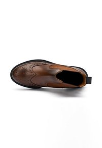 Scarpa slip-on in pelle marrone con dettagli a brogue, perforazioni e pannelli laterali elasticizzati, vista dall'alto su uno sfondo bianco.