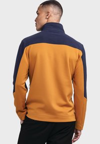 Fleece-Pullover mit einem strukturierten, orangefarbenen Körper und einem navyblauen oberen Abschnitt. Verfügt über einen hohen Kragen und Reißverschlusselemente.