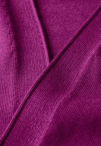 Tissu tricoté dans une teinte violette vibrante, avec des textures variées comprenant des surfaces lisses et côtelées, créant des contrastes visuels distincts.