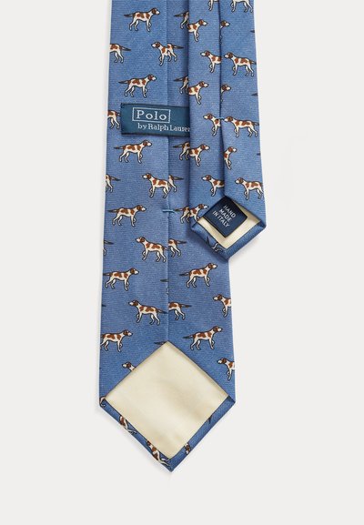 Niebieski jedwabny krawat z powtarzającym się wzorem psów w brązie i bieli, z kremową podszewką. Etykieta głosi „Polo by Ralph Lauren”.